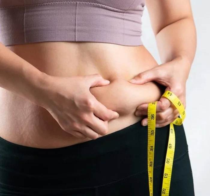 Woman measuring her waist with a tape measure